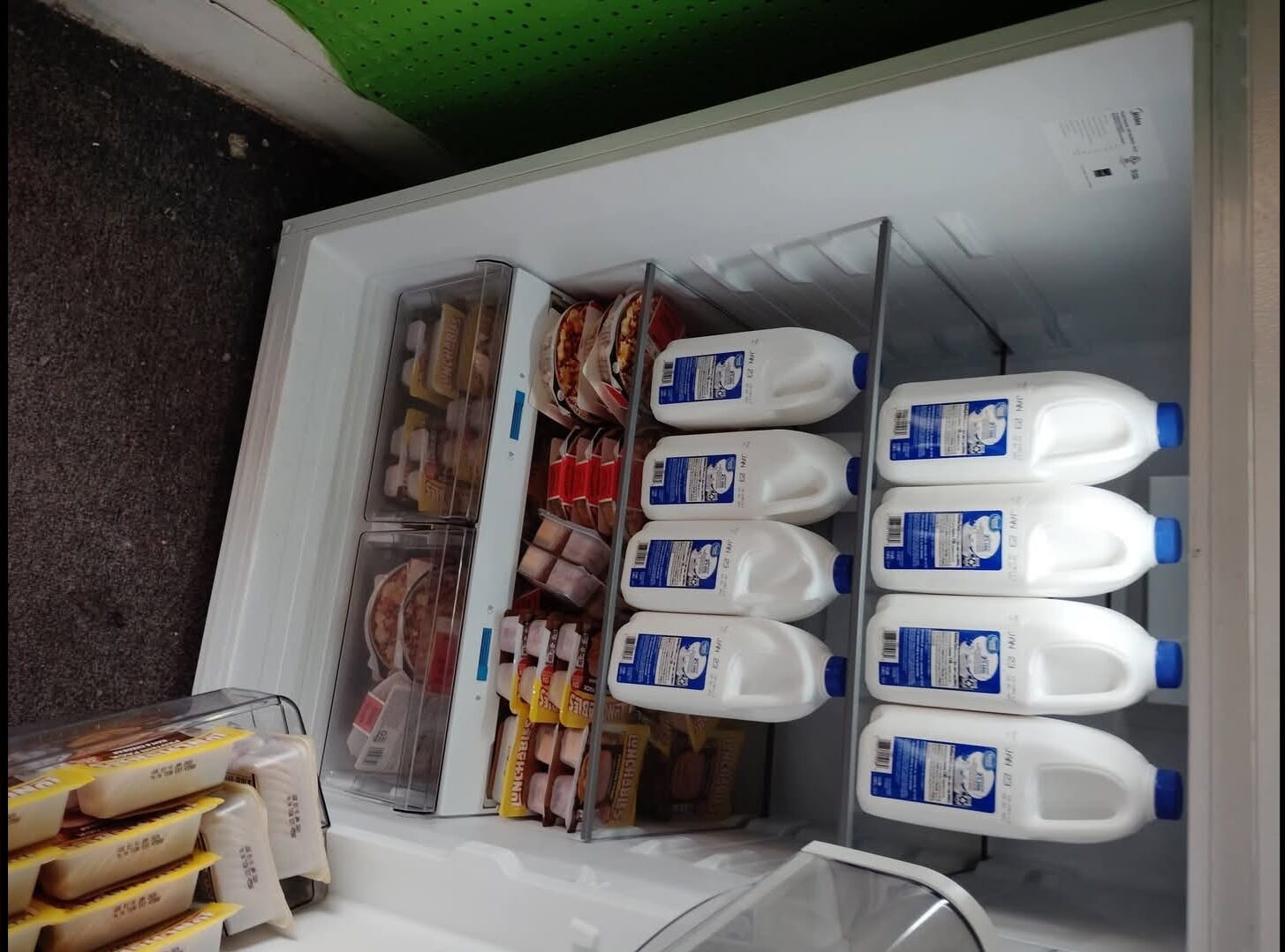 An open fridge filled with milk and other staple foods