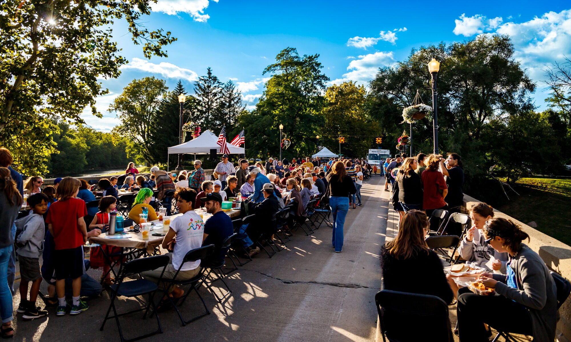 A view down the Washington St. Bridge lined with tables full of people enjoying the dinner