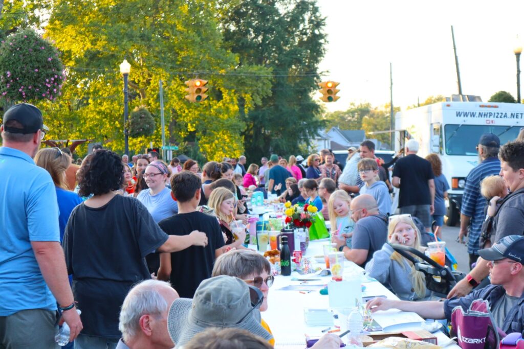 A packed photo of the crowd on the bridge with the row of tables down the center and food trucks at the end. The stoplights are visible along the upper edge of the frame.