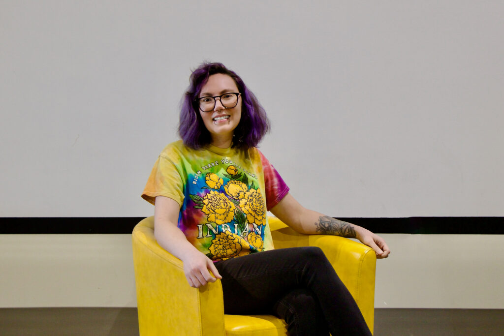 Paige Waters, one of the 2026 CenterPoint Scholars, sits in a yellow arm chair, smiling at the camera.